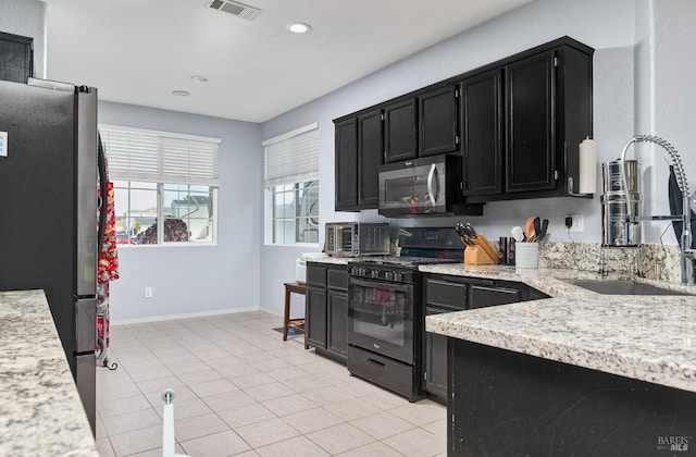 kitchen with a sink, appliances with stainless steel finishes, visible vents, recessed lighting, and dark cabinetry