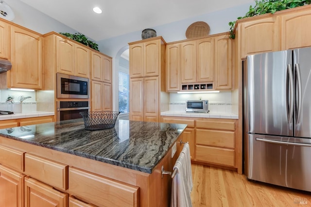 kitchen featuring light brown cabinetry, appliances with stainless steel finishes, and light wood-style floors