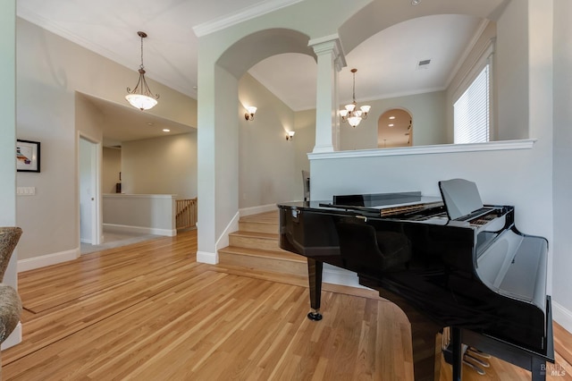 living area featuring baseboards, ornate columns, wood finished floors, and visible vents