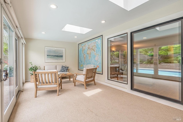 living area featuring recessed lighting, a skylight, light colored carpet, and baseboards