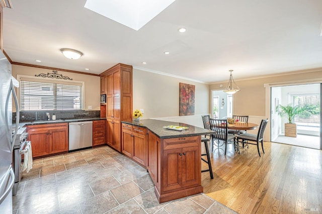kitchen featuring crown molding, appliances with stainless steel finishes, a peninsula, and a wealth of natural light