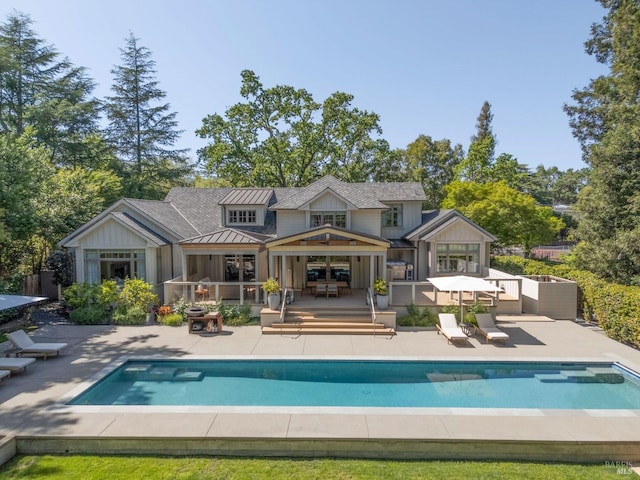 back of property featuring a standing seam roof, a patio, board and batten siding, and an outdoor pool