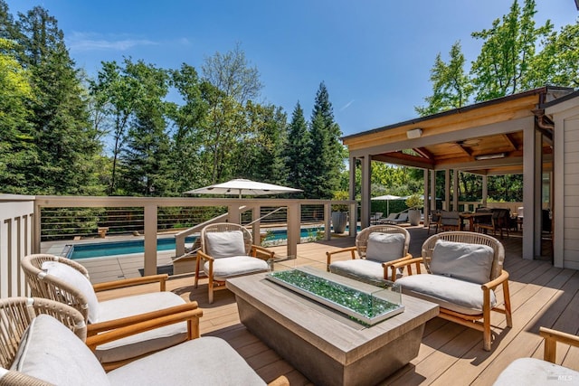 wooden terrace featuring an outdoor living space with a fire pit and an outdoor pool