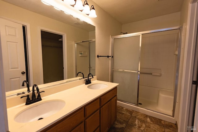 bathroom featuring a stall shower, double vanity, and a sink