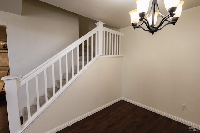 staircase with wood finished floors, a notable chandelier, and baseboards