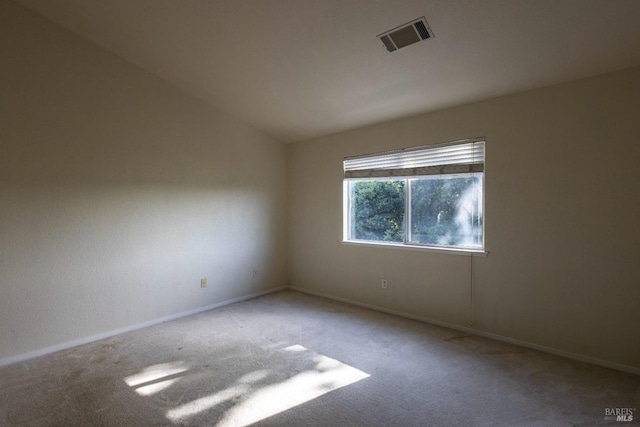 empty room featuring visible vents, baseboards, vaulted ceiling, and carpet floors