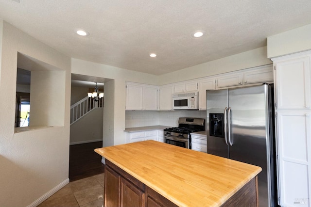 kitchen with butcher block countertops, white cabinetry, stainless steel appliances, and baseboards