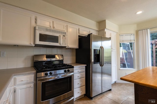 kitchen featuring decorative backsplash, light tile patterned floors, appliances with stainless steel finishes, light countertops, and white cabinetry