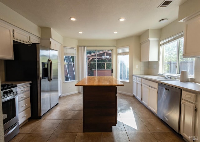 kitchen featuring a sink, visible vents, stainless steel appliances, a kitchen island, and a healthy amount of sunlight