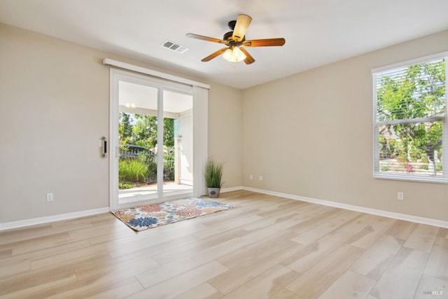 spare room featuring visible vents, light wood-style flooring, and a healthy amount of sunlight