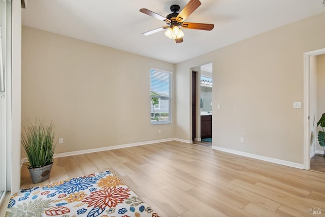 unfurnished room featuring a ceiling fan, light wood finished floors, and baseboards