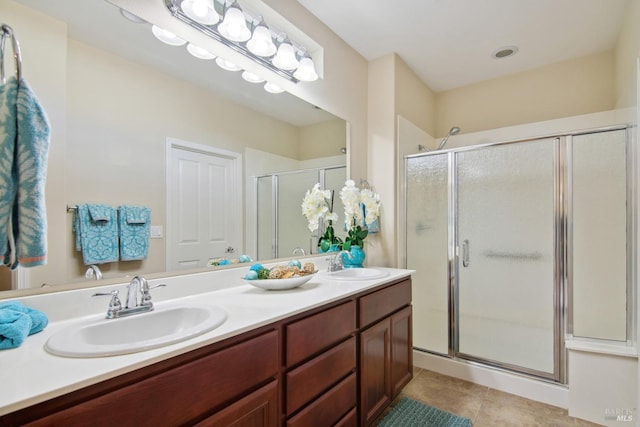 full bathroom with tile patterned floors, a stall shower, double vanity, and a sink