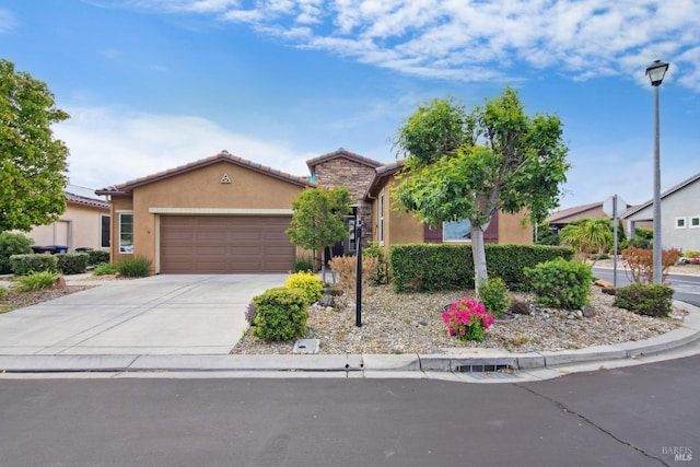 view of front facade with concrete driveway, a garage, stucco siding, and a tiled roof