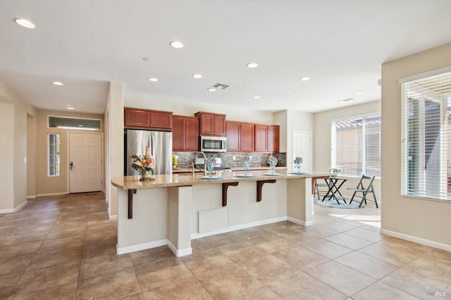 kitchen featuring tasteful backsplash, a spacious island, visible vents, stainless steel appliances, and light tile patterned flooring