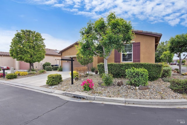 view of front of property with stucco siding, a tiled roof, driveway, and a garage
