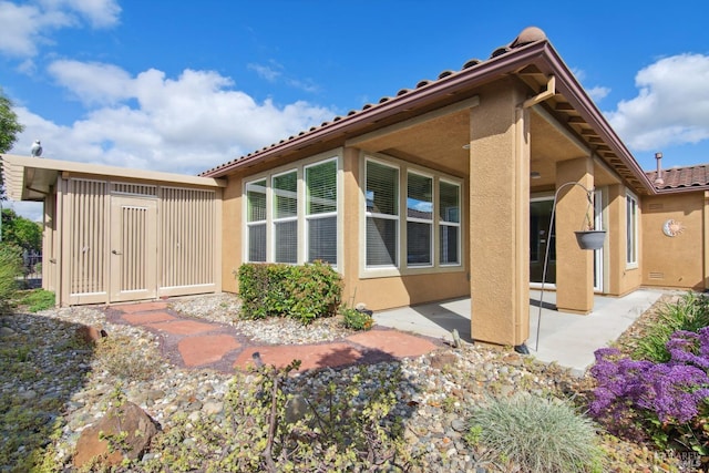 back of property featuring stucco siding, a patio area, and a tile roof