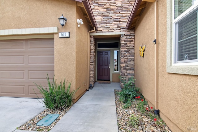 view of exterior entry featuring a garage, stucco siding, and stone siding