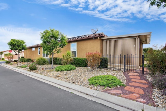 view of side of home with fence, stucco siding, and a tiled roof
