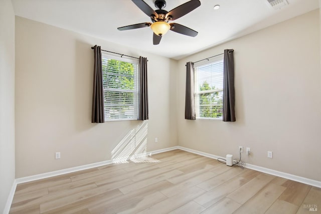 spare room with baseboards, visible vents, ceiling fan, and light wood-style floors