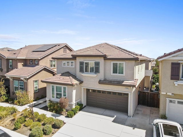 view of front of home featuring driveway, a tile roof, stucco siding, fence, and a garage