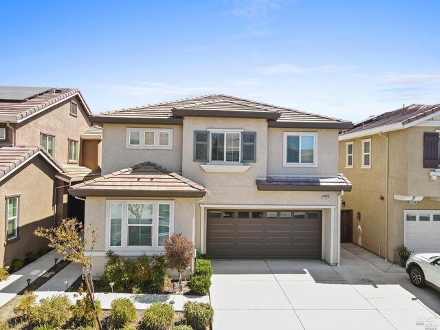 view of front of property with driveway, an attached garage, a tiled roof, and stucco siding