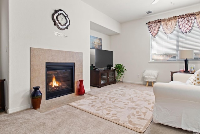 carpeted living area featuring a tiled fireplace, visible vents, and ceiling fan