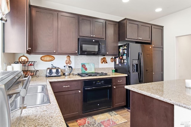 kitchen with black appliances, recessed lighting, dark brown cabinetry, and light wood-style floors
