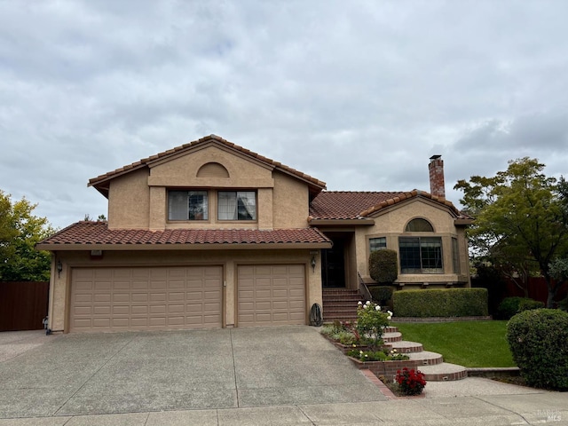 mediterranean / spanish house with a chimney, stucco siding, a garage, a tile roof, and concrete driveway