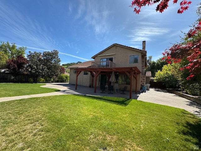 rear view of property with stucco siding, fence, a patio, driveway, and a lawn