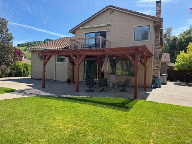 back of property with a chimney, stucco siding, a yard, a tiled roof, and a patio