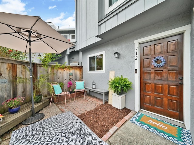 entrance to property with fence and stucco siding