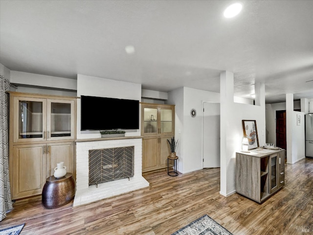 living area featuring a fireplace, wood finished floors, and baseboards