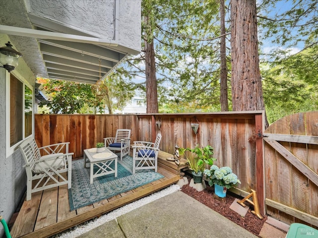view of patio / terrace featuring an outdoor living space, a deck, and a fenced backyard