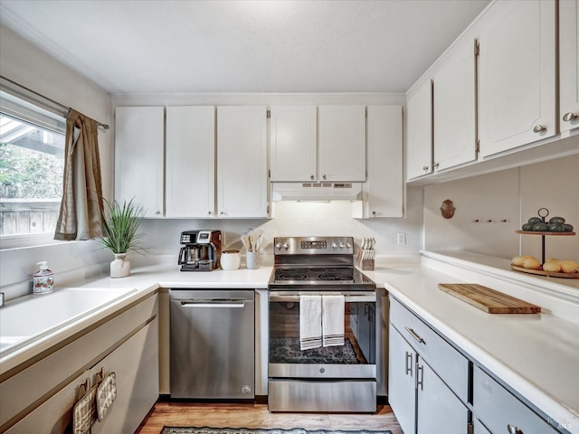 kitchen featuring appliances with stainless steel finishes, light countertops, white cabinets, and under cabinet range hood