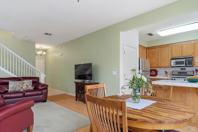 dining area with an inviting chandelier, stairs, visible vents, and light wood-type flooring