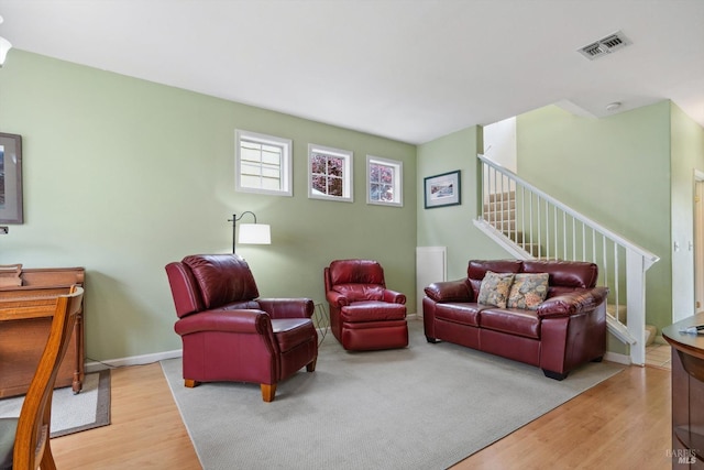 living room featuring stairs, wood finished floors, and visible vents
