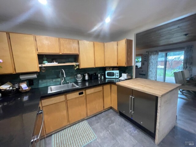 kitchen with under cabinet range hood, dark countertops, appliances with stainless steel finishes, and tasteful backsplash