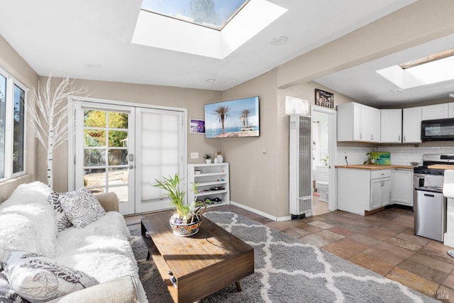 living area featuring a heating unit, a skylight, stone finish floor, and baseboards