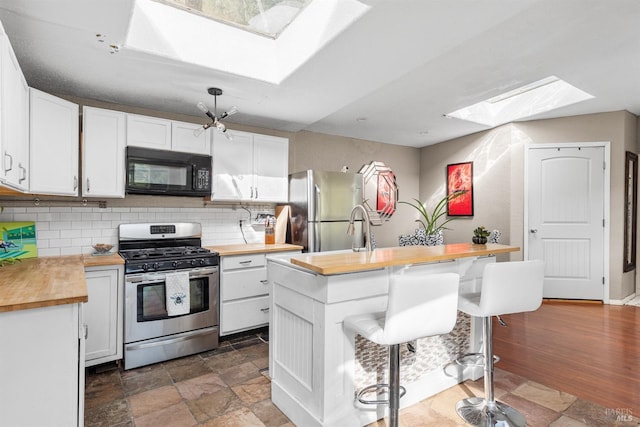 kitchen featuring white cabinetry, a skylight, appliances with stainless steel finishes, and wooden counters