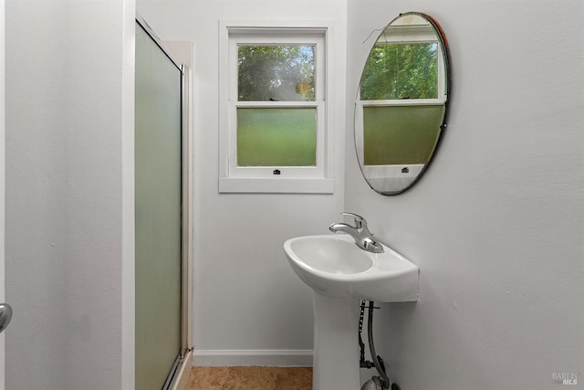 full bath with a shower stall and baseboards