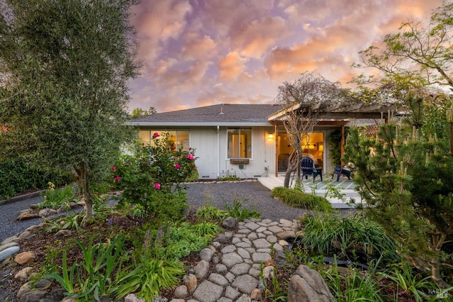 back of house at dusk featuring a patio area
