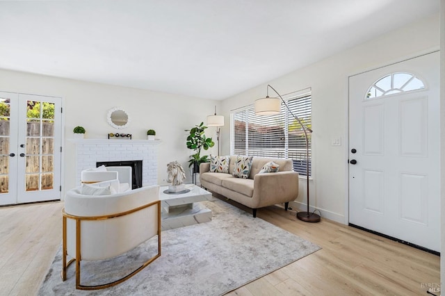 living room featuring french doors, a brick fireplace, and light wood-type flooring