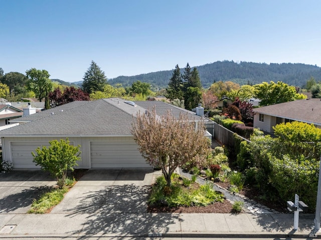 view of front facade with an attached garage, driveway, a mountain view, and roof with shingles