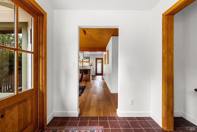 corridor with dark tile patterned flooring and baseboards