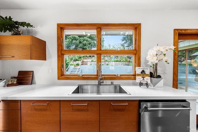 kitchen with a sink, light countertops, modern cabinets, and stainless steel dishwasher
