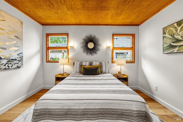 bedroom featuring baseboards, ornamental molding, wood ceiling, and wood finished floors