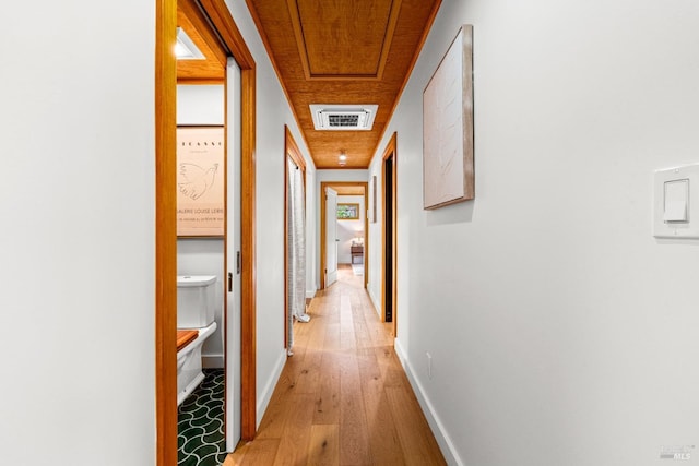 hallway featuring baseboards, visible vents, and light wood-style flooring