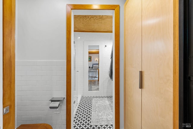 hallway featuring wainscoting and tile walls