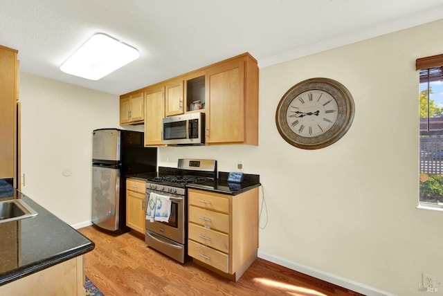 kitchen featuring baseboards, light wood-style flooring, appliances with stainless steel finishes, and light brown cabinets