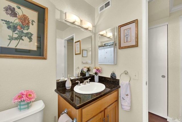 bathroom with vanity, toilet, and visible vents